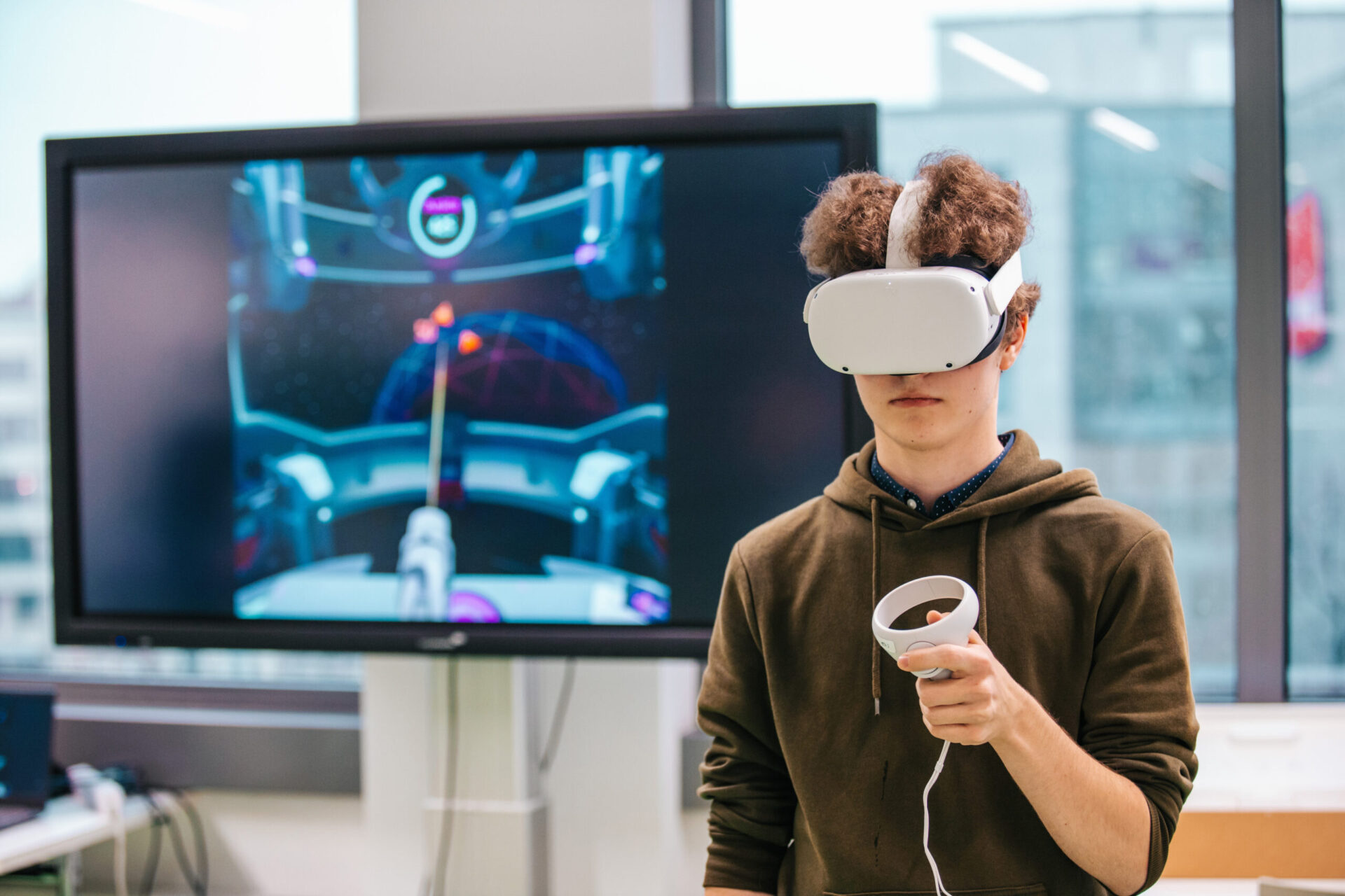 Schüler trägt VR-Brille und hält eine Fernbedienung in der Hand.